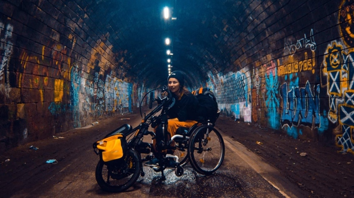 a woman with a handcycle on a cycle ride in a tunnel which is covered in graffitti