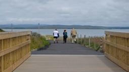 Three people crossing a bridge on the Loch Indaal Way.