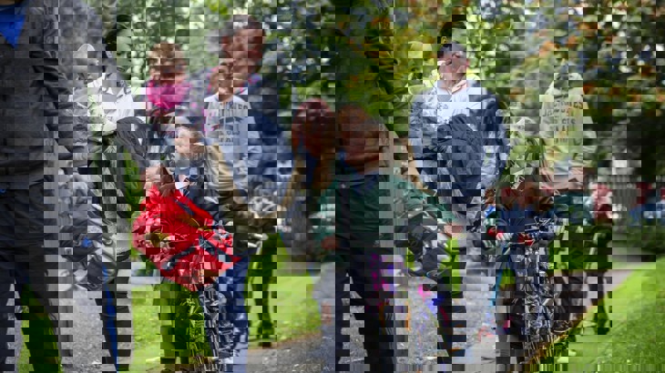 adults and children walking and scooting to school on footpath