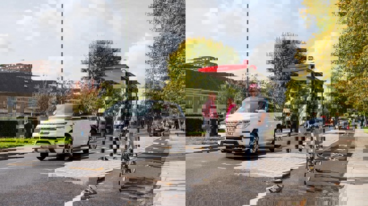 Man on bicycle on protected cycle lane, passing a bus stop