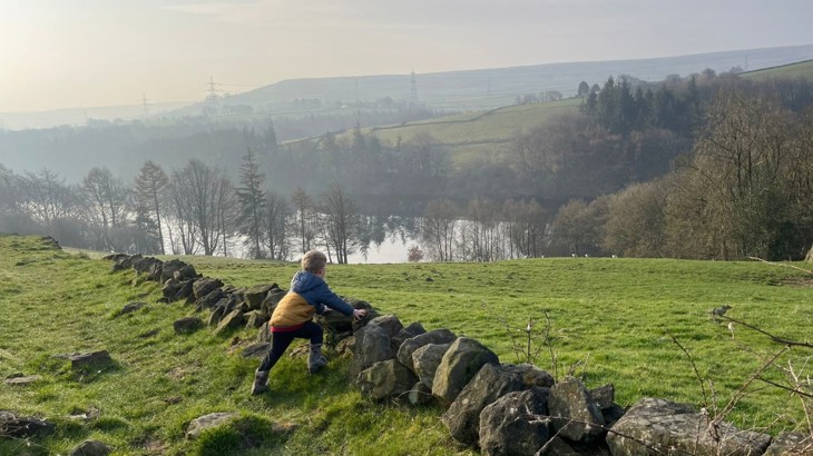 Little boy leaning over a stone wall looking at the countryside views on his commute to school as part of Walk Wheel Cycle Trust Big Walk and Wheel