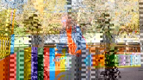 girl cycling past colourful fence