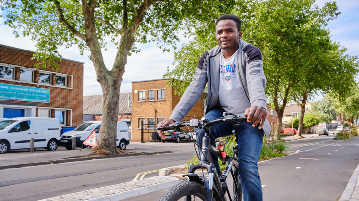 Man smiles as he cycles along a quiet segregated cycle lane in Bristol.