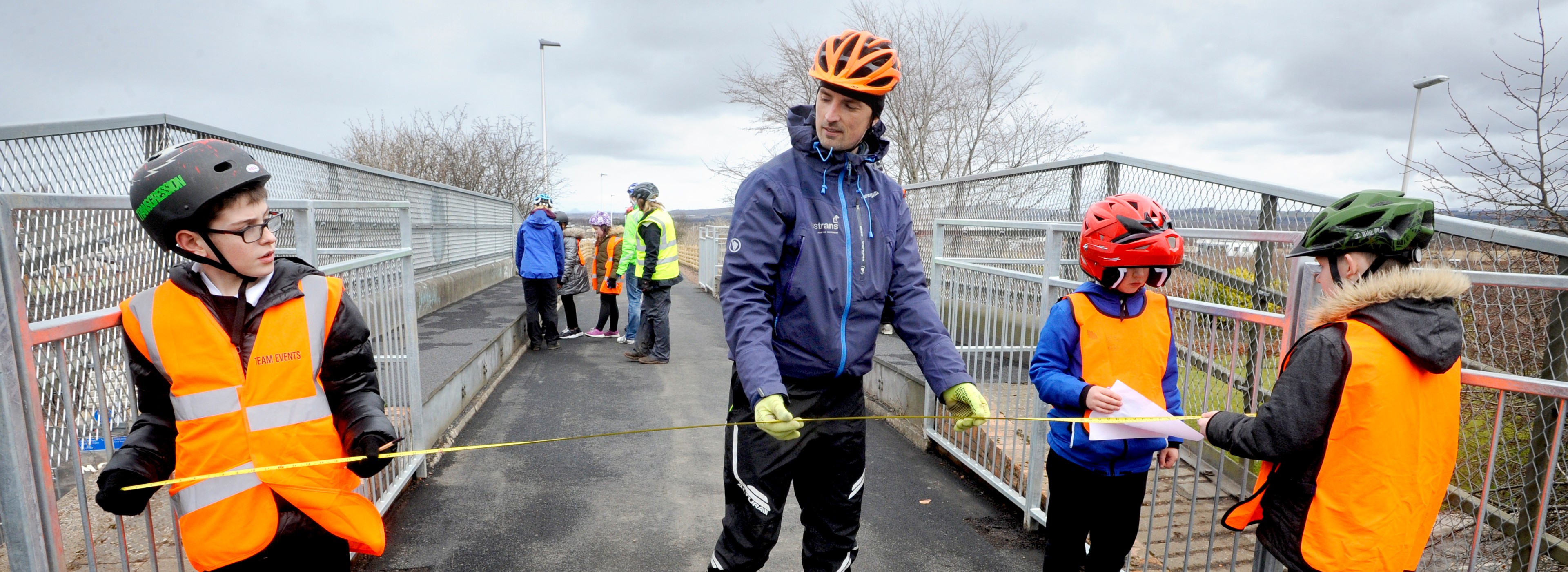 school children and Walk Wheel Cycle Trust engineer measuring a footbridge