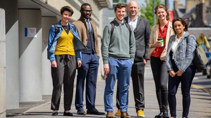 A group of employees pose outside their office