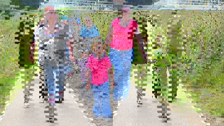 A family walk together along a traffic free route surrounded by bushes