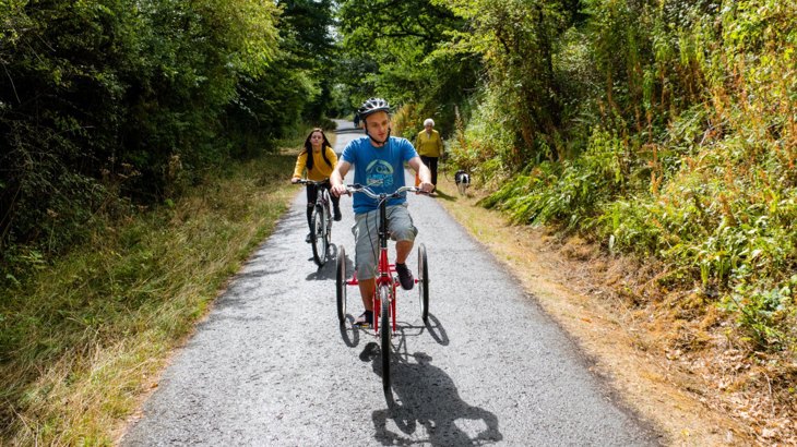 Two people cycling and one walking a dog on the Bristol and Bath Railway Path