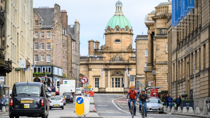 Two people cycle on George IV bridge in Edinburgh
