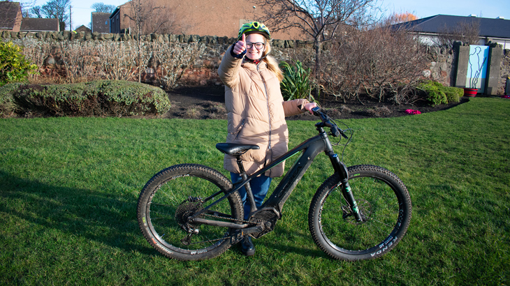 Teenage girl posing with her bike giving a thumbs up and smiling