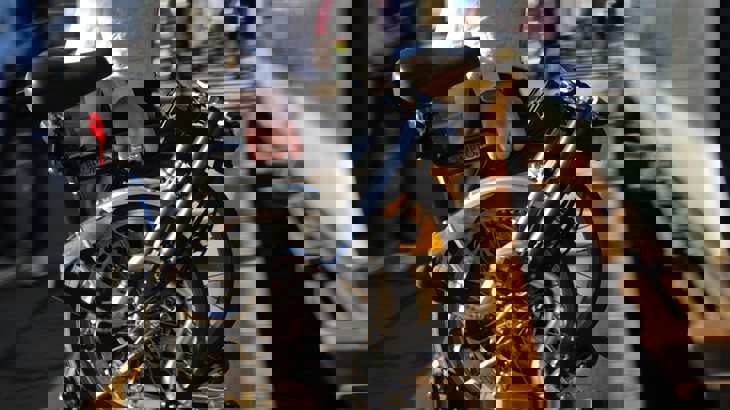 A person in white jacket carrying Brompton bike onto a train