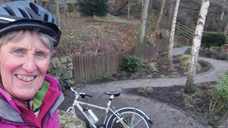 Karen is shown in this selfie on a cycle track with her bicycle behind her. 