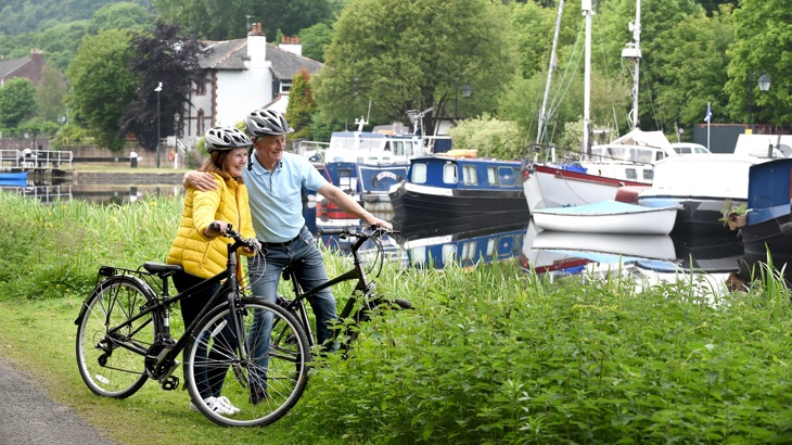 A couple is shown standing with bicycles enjoying an urban stretch of NCN 745 at Maryhill Locks, Glasgow