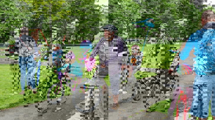 Dad with daughter in bike seat and other child on own bike next to him