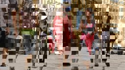 Two female friends walking through high street with others walking in the background