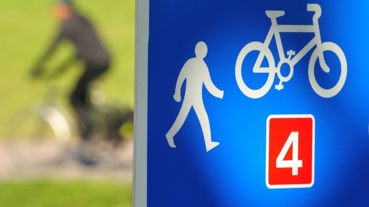 person cycling past national cycle network sign for route 4