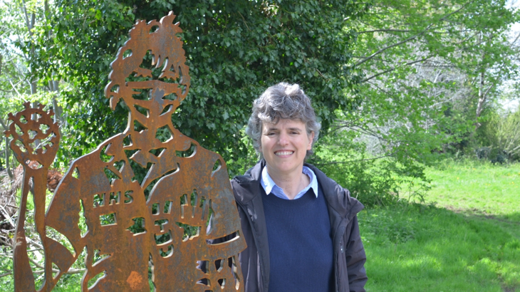 Local GP stands next to portrait bench recognising NHS staff on the National Cycle Network in Lawrence Weston, Bristol.