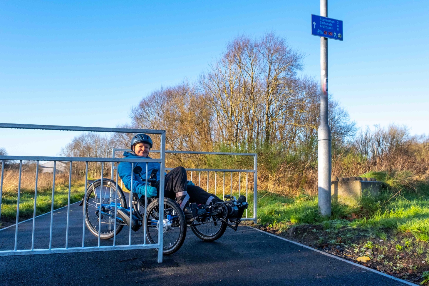 A woman on a recumbent cycle on a section of the National Cycle Network in between a chicane barrier