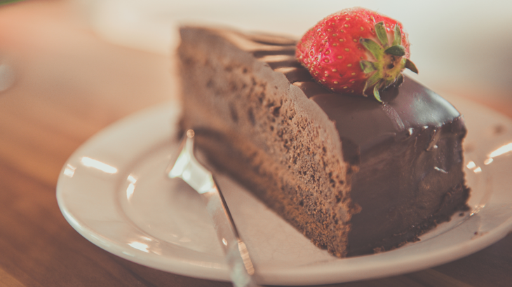Slice of chocolate cake with strawberry on top.