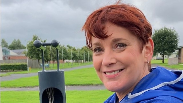 A woman with short red hair is looking straight at the camera and smiling.