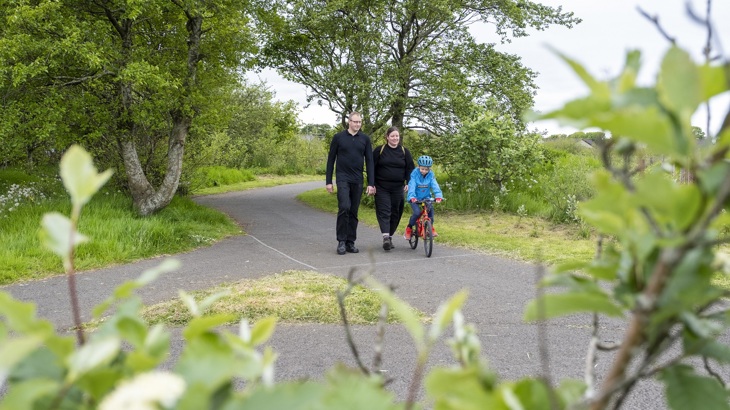 Adele and Rikki Lidderdale are pictured walking in Papdale Park, Orkney. They are following their son Remi, who is riding a bicycle.