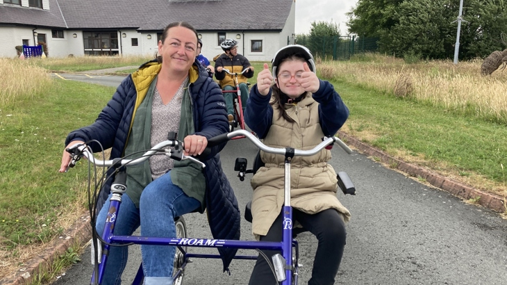 A parent and child from Ysgol Pendalar, Caernarfon, taking part in a sponsored walk and wheel.
