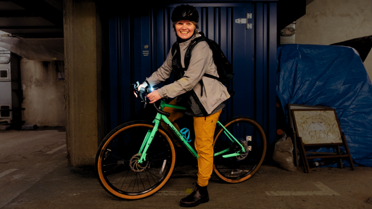 Woman holding a bike and smiling at the camera.