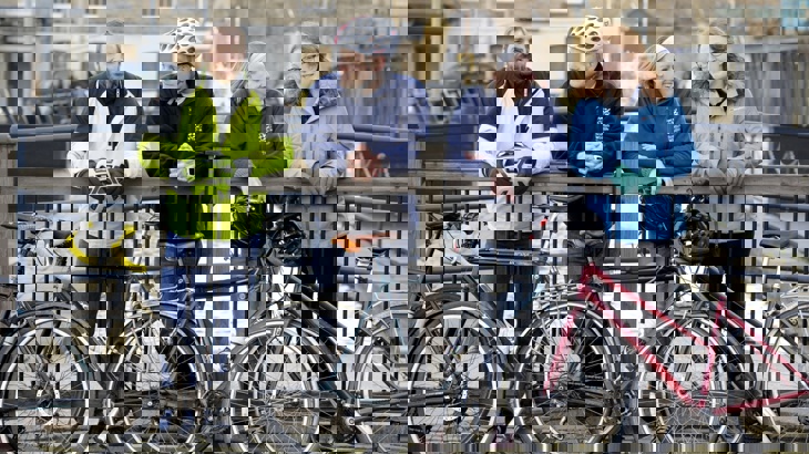A group of colleagues, two male and two female, posing near a canal with their bicycles