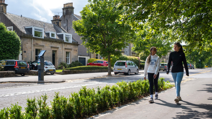 Two young people walking on a residential street on a sunny day
