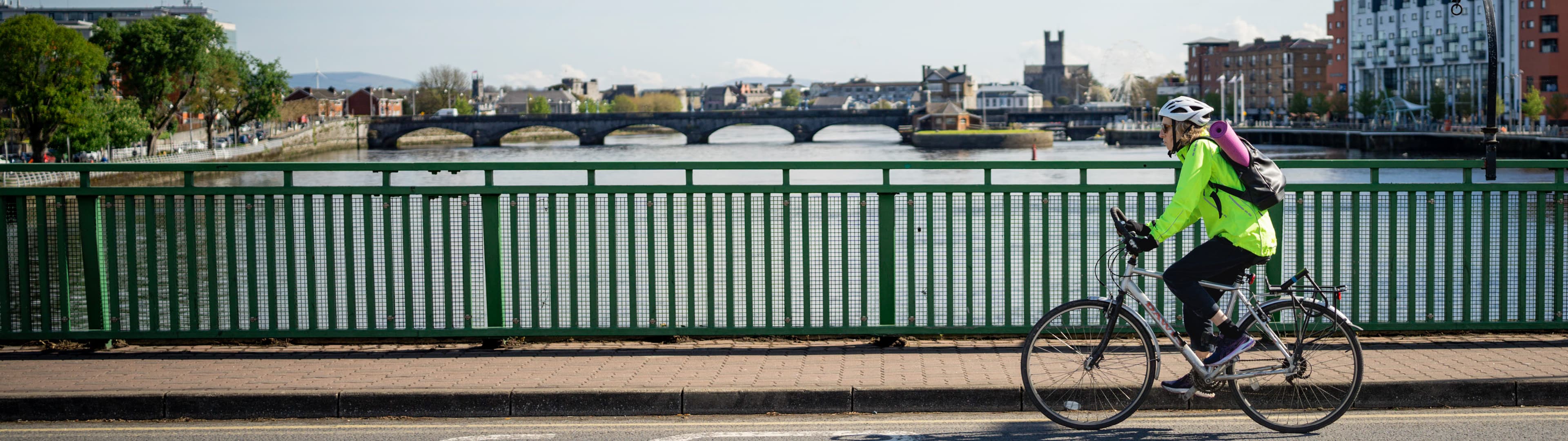 Female cyclist on bridge in segregated cycle lane alongside vehicle traffic in Limerick city centre.