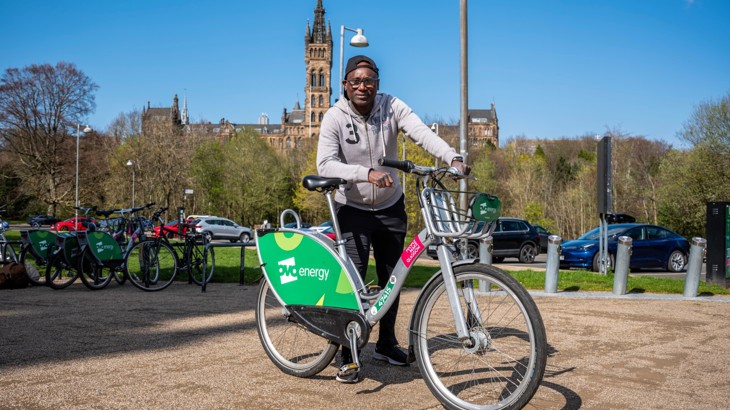 Sekou, a respondent in the Walking and Cycling Index report, stands with a hired bike in the centre of Glasgow on a cold, clear sunny day.