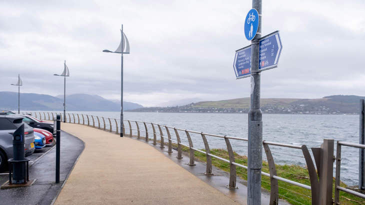 A shared-use traffic-free path at Gourock Station with the River Clyde to the right and hills in the background.