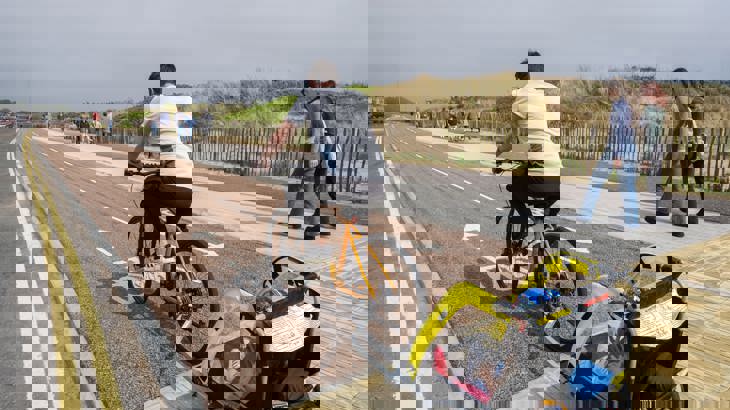 Male Cyclist With Child In Trailer On Cycle Path