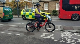 Riding upright trike in 2-way protected cycle lane, while an ambulance in 2-way mixed traffic, is passing a bus