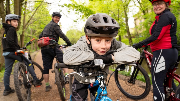 family on bikes have a break on a towpath and smile at camera