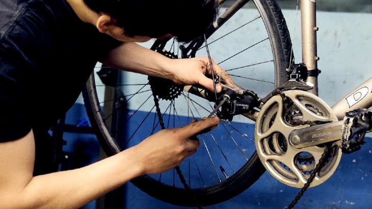 A volunteer is shown working on a bicycle in the workshop.