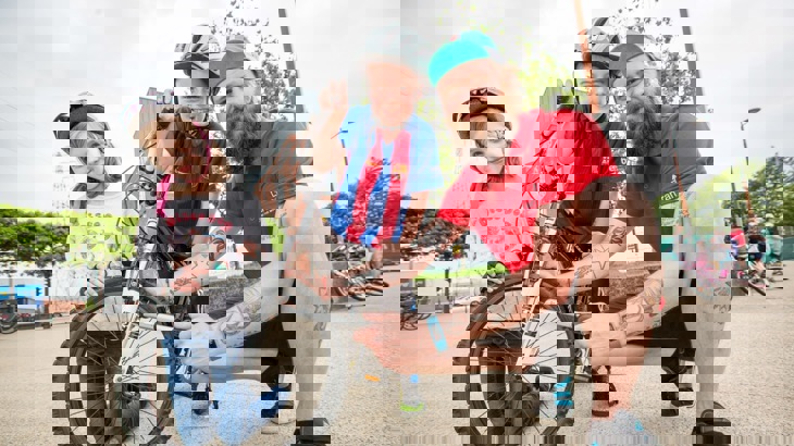 Walk Wheel Cycle Trust schools officer fixing a bike with two children