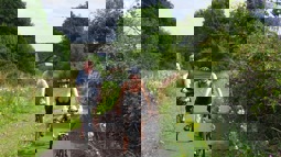 Man and woman cycling on greenway with bridge in the background