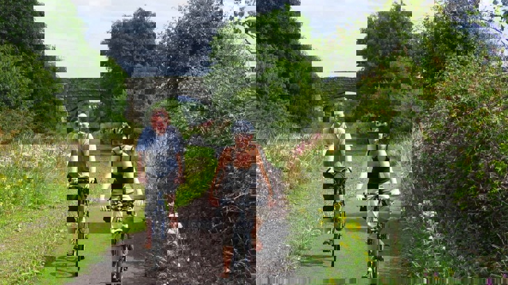 Man and woman cycling on greenway with bridge in the background