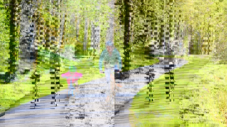 Man and child cycling on a greenway path