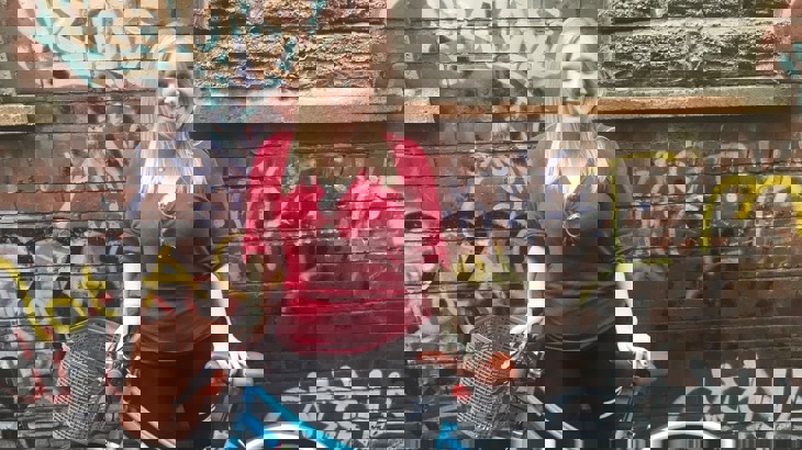 Gwyneth poses with her bike in front of a wall