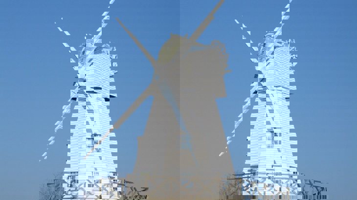 White wooden windmill against blue sky