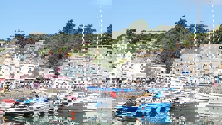 Town harbour with yachts and smaller boats, with shops and houses surrounding the harbour