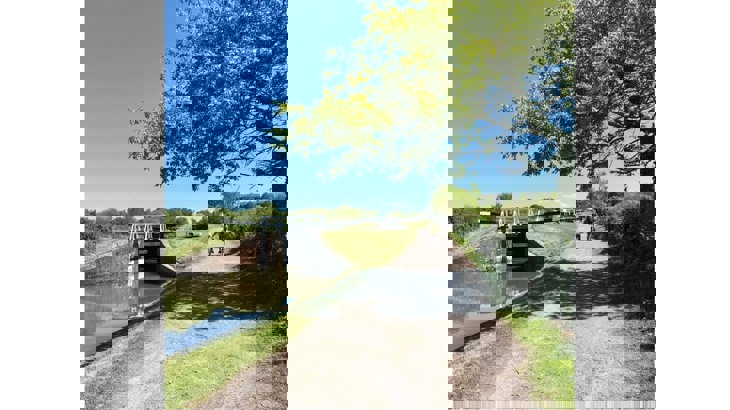 Adult and child cycling along canal towpath with locks to the side