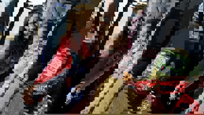 A mum fastens her daughter's seat belt in the car after going shopping