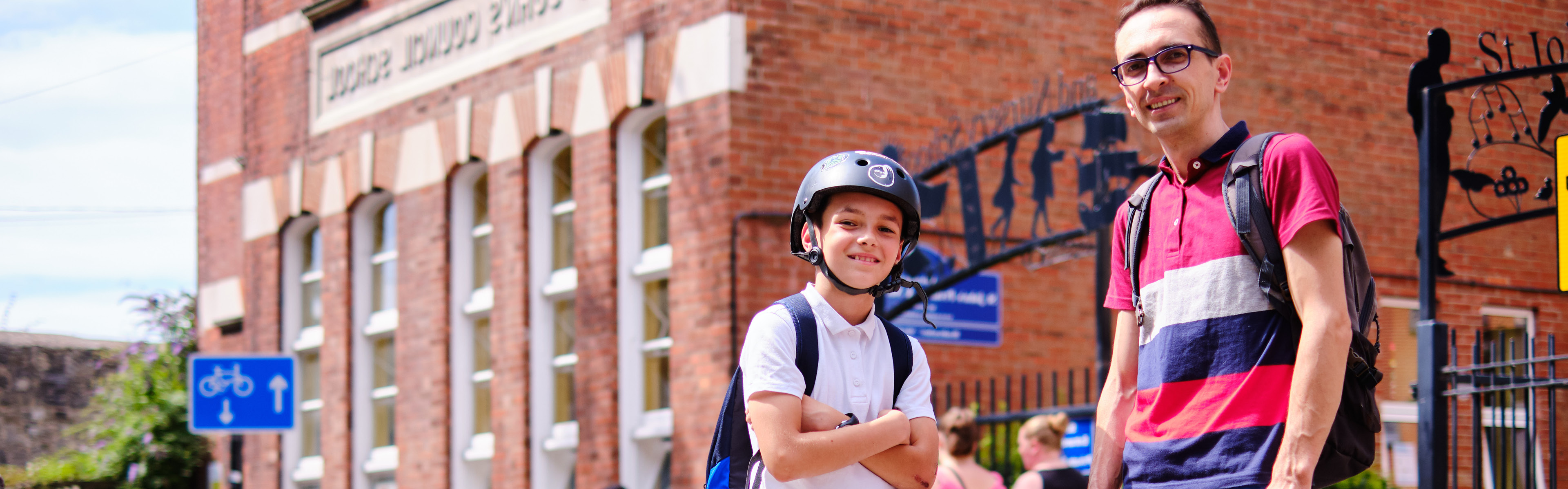 Dad and son with their bicycles stood outside of school
