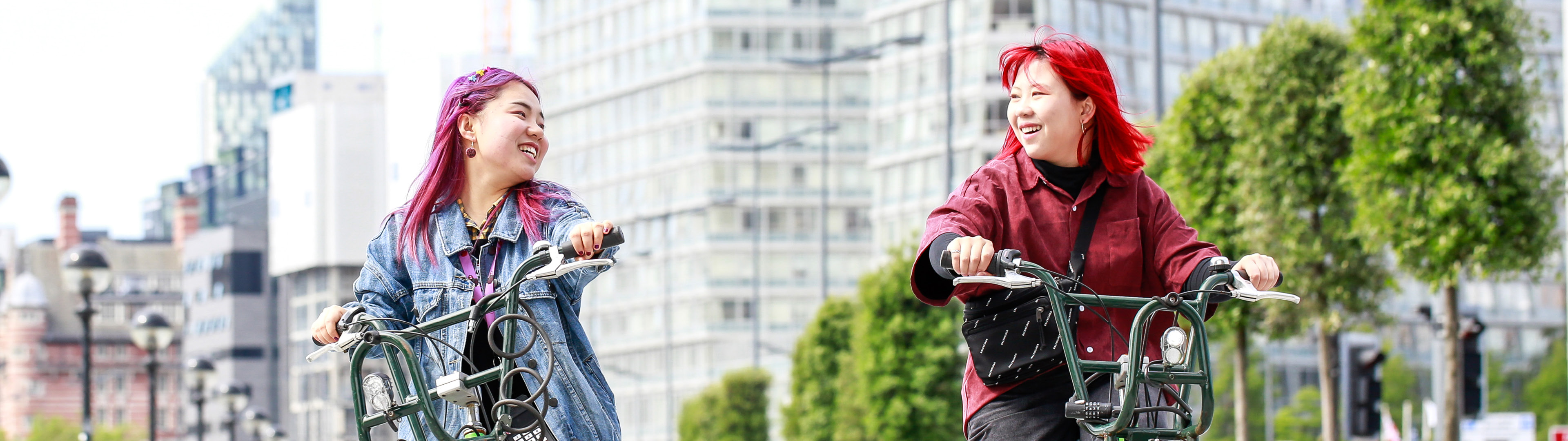 Two girls smiling as they cycle along the docks in Liverpool