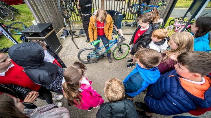A Walk Wheel Cycle Trust staff member delivers a Dr Bike maintenance session to a class of primary school pupils.