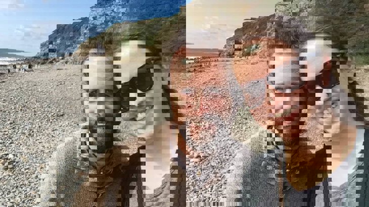 Kristen wearing sunglasses pictured with her husband on a beach