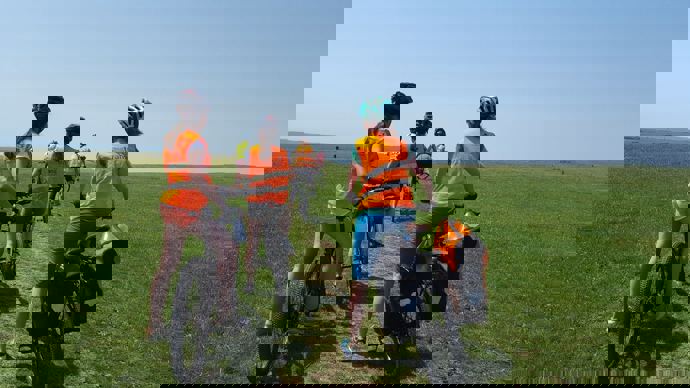 girls on bikes in Walk Wheel Cycle Trust hivis on a grass hill with blue skies