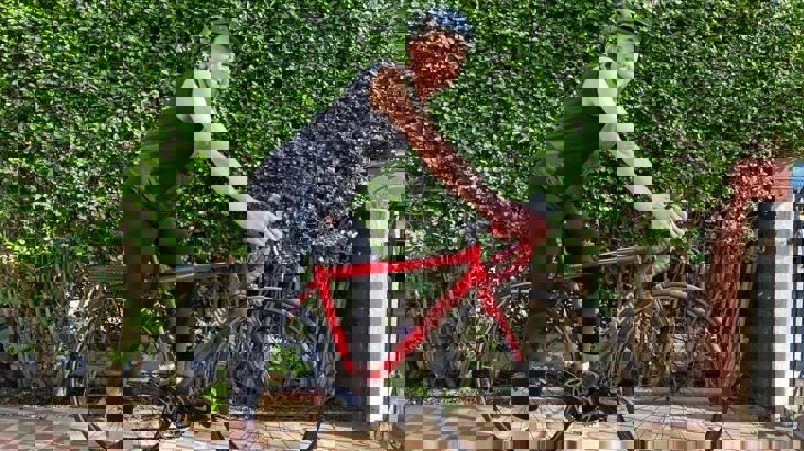 Kirsten, wearing a helmet and stood with her bike smiling at the camera